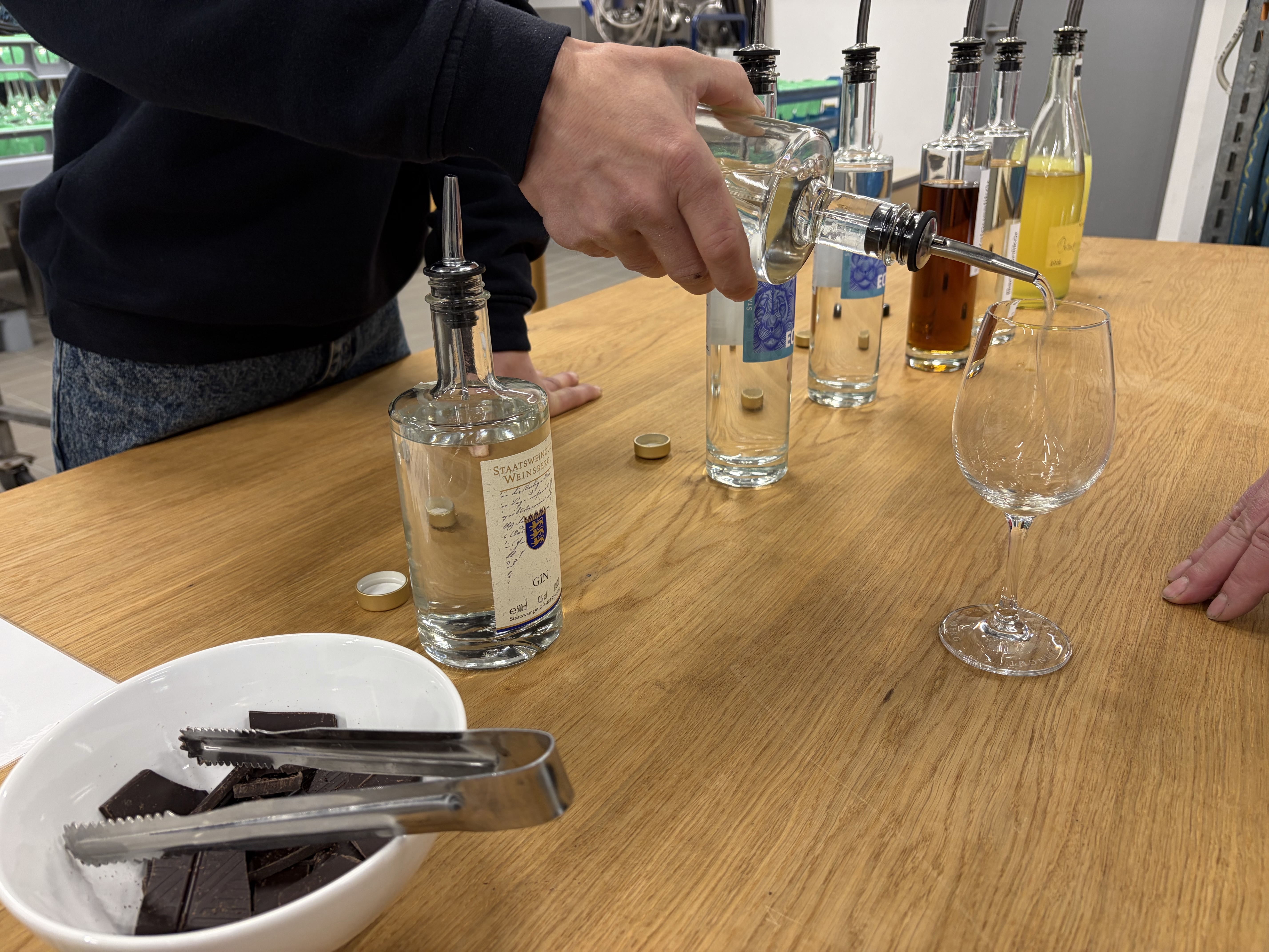 Person gießt Spirituosen zur Verkostung in Gläser. 