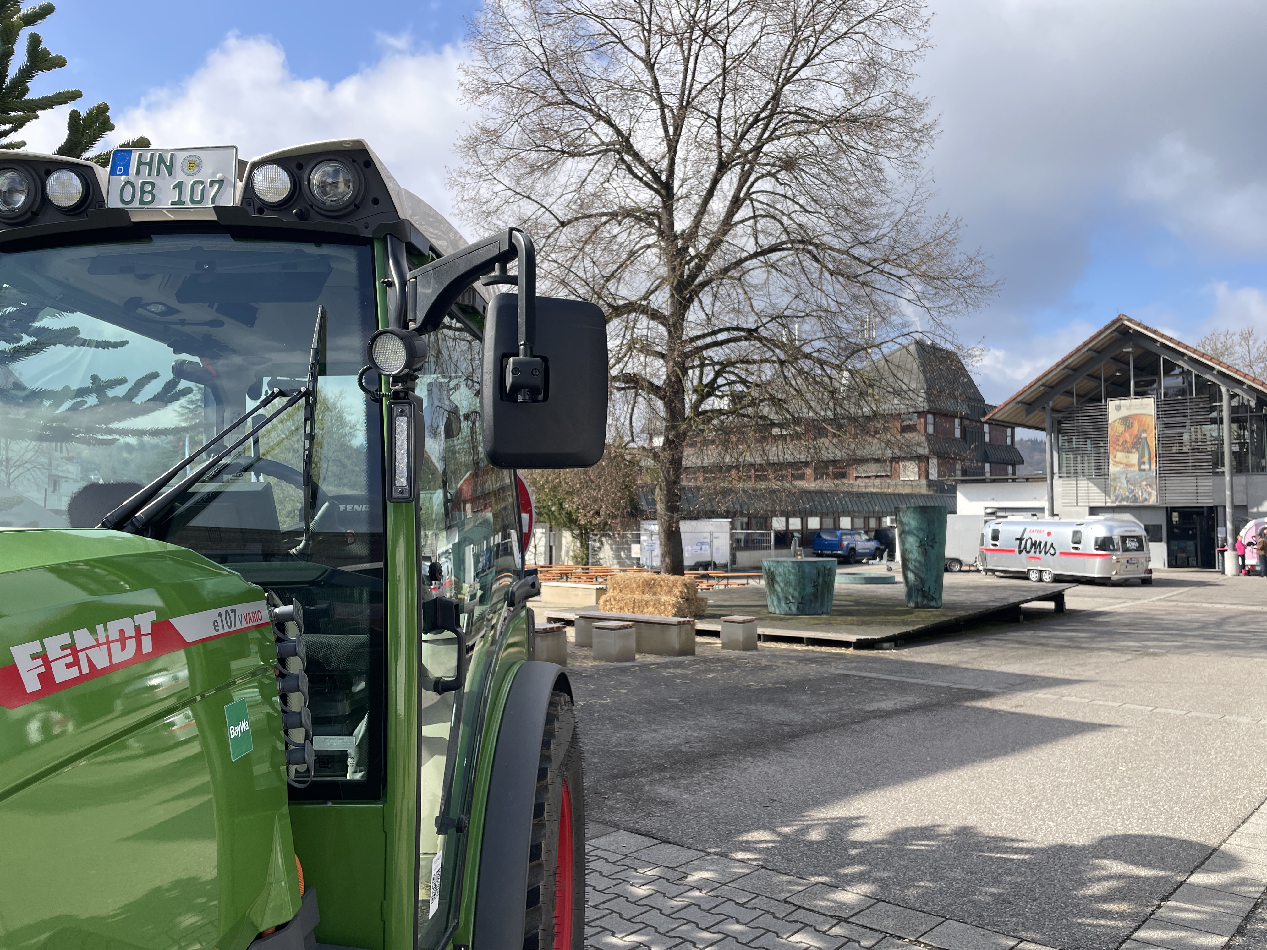 Im Vordergrund steht ein Fendt-Traktor und im Hintergrund ist das Kellerei-Gebäude der LVWO Weinsberg zu sehen. 